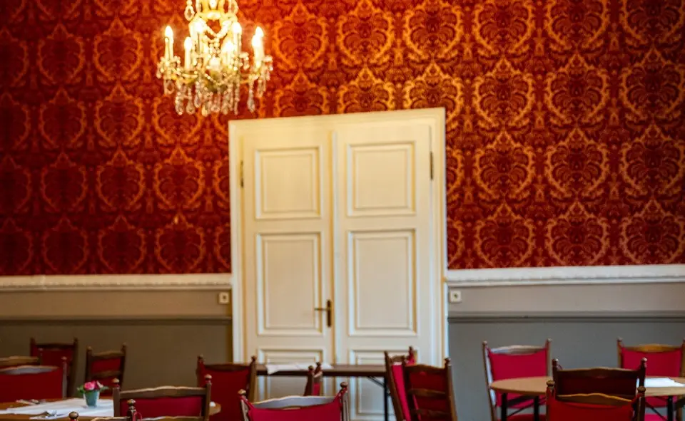 Festsaal mit rotem Wandmuster und Kronleuchter